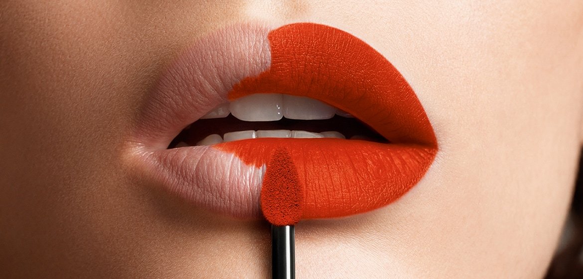 Volle Lippen werden mit einem kräftigen Rotorange Ton gefärbt